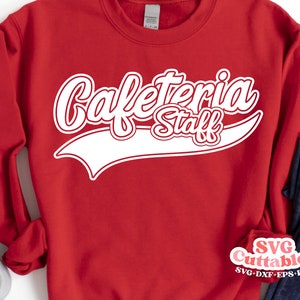 May include: Red sweatshirt with white text that says "Cafeteria Staff" in a vintage baseball jersey style font.