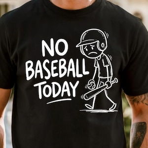 Könnte beinhalten: Schwarzes T-Shirt mit dem weißen Text "NO BASEBALL TODAY" und einem traurigen Cartoon-Baseballspieler, der einen Schläger und einen Ball hält. Die Illustration zeigt eine niedergeschlagene Figur mit einem Baseballhelm.