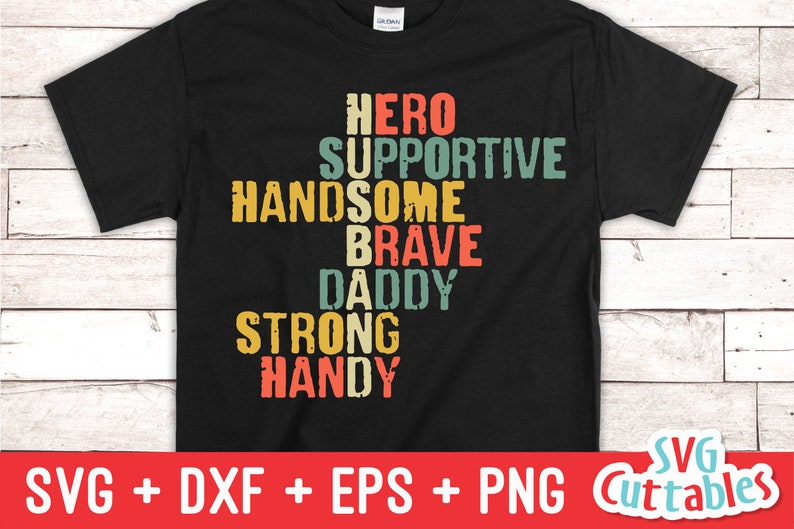 May include: A black t-shirt with a vintage-style design featuring the words "Hero", "Supportive", "Handsome", "Brave", "Daddy", "Strong", and "Handy" arranged in a crossword puzzle pattern.
