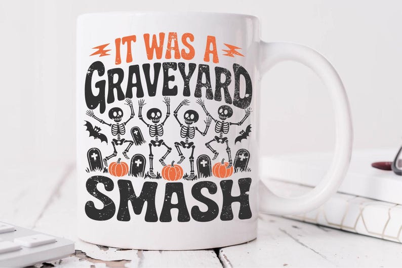 May include: White ceramic mug with a Halloween-themed design. The mug features the text "IT WAS A GRAVEYARD SMASH" in orange and black, along with illustrations of dancing skeletons, pumpkins, and tombstones. A perfect gift for Halloween.