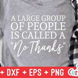 Może przedstawiać: Szary T-shirt z nadrukiem "A large group of people is called a "No Thanks"" w kolorze białym. T-shirt leży na białej powierzchni z cegły, obok znajduje się koszula w kratę i czarno-białe buty.