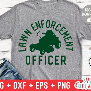May include: A gray t-shirt with a green lawnmower graphic and the text "Lawn Enforcement Officer".