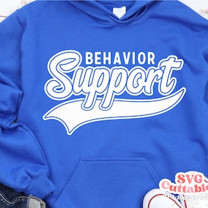 May include: A royal blue hoodie with a white graphic that says "Behavior Support" in a vintage baseball font.