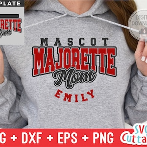 May include: Gray hooded sweatshirt with the text "MASCOT MAJORETTE Mom EMILY" in red and black lettering. The text is in a varsity style font. The sweatshirt is a digital download and includes SVG, DXF, EPS, and PNG files.