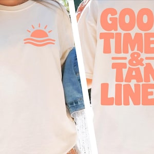 Puede incluir: Camiseta color crema con un sol y olas coral en la parte delantera. La parte trasera de la camiseta presenta el texto "GOOD TIMES & TAN LINES" en negrita, coral. Una prenda informal con temática playera.