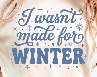 以下が含まれることがあります： クリーム色のスウェットシャツ。青い文字で「I wasn't made for WINTER」と書かれています。デザインには雪の結晶、星、ハートが含まれています。冬をテーマにしたグラフィックTシャツ。
