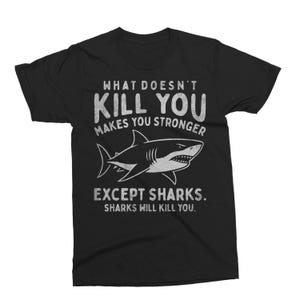 May include: Black t-shirt with a white shark graphic and text that reads "WHAT DOESN'T KILL YOU MAKES YOU STRONGER EXCEPT SHARKS. SHARKS WILL KILL YOU."