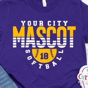 以下が含まれることがあります： 紫色のTシャツに「YOUR CITY MASCOT SOFTBALL」という文字が白と黄色で書かれています。「MASCOT」という文字は、黄色い背景に大きく太字で書かれています。「SOFTBALL」という文字は、黄色のソフトボールと「18」という数字が書かれた円の中にあります。