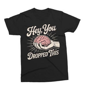 May include: Black t-shirt featuring a graphic design with the text "Hey, You Dropped This." The design includes a hand holding a pink brain, with radiating lines. The text and design are in white and pink.