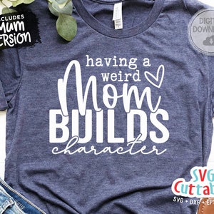 May include: A blue t-shirt with white text that reads "having a weird mom builds character" with a small heart symbol. The text is in a handwritten font.