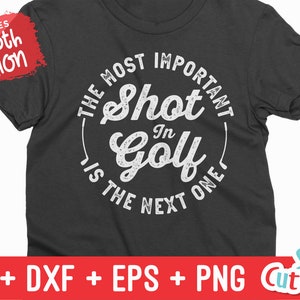 K&ouml;nnte beinhalten: Ein dunkelgraues T-Shirt mit einem wei&szlig;en Kreis-Motiv, auf dem "Der wichtigste Schlag im Golf ist der n&auml;chste" steht.