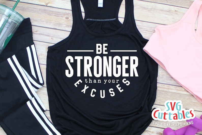 May include: Black tank top with white text that reads "BE STRONGER than your EXCUSES". The tank top is laying on a wooden surface with a pair of black leggings with white stripes, a pink tank top, and pink weights.