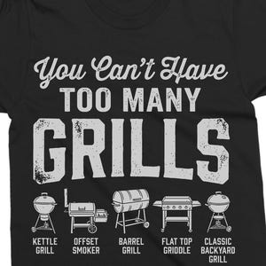 May include: Black t-shirt with the text "You Can't Have Too Many Grills" in white, along with illustrations of different grill types: kettle, offset smoker, barrel, flat top griddle, and classic backyard grill.