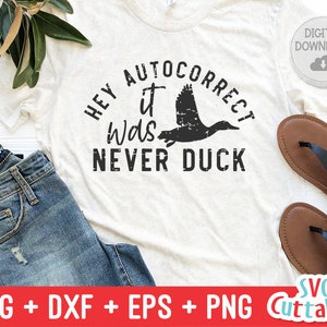 May include: A white t-shirt with the text "HEY AUTOCORRECT IT WAS NEVER DUCK" in black lettering. A black silhouette of a duck is flying above the text.