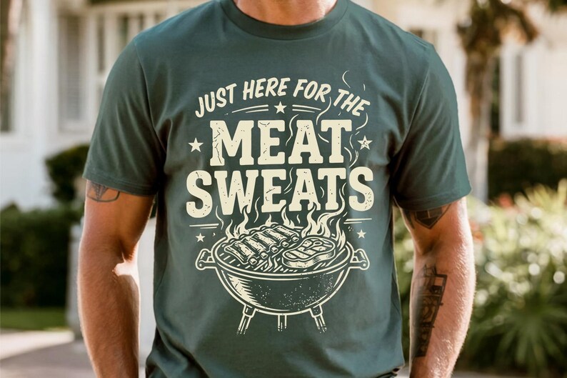 May include: Dark green t-shirt with the text "JUST HERE FOR THE MEAT SWEATS" in a distressed, vintage style. The design includes a grill with ribs and steak. A casual tee for grilling enthusiasts.