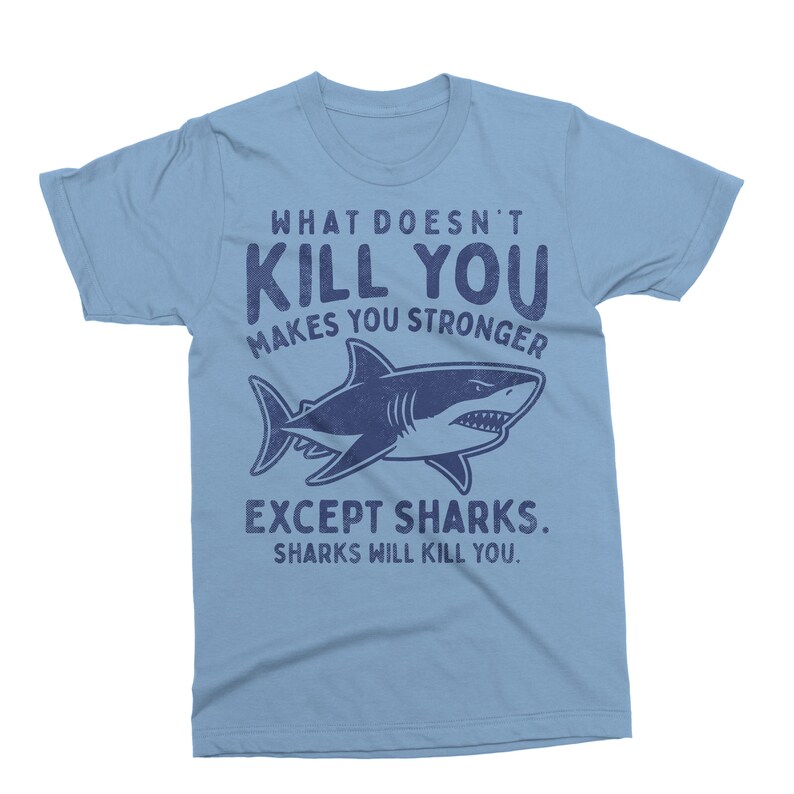May include: Light blue t-shirt with the text "WHAT DOESN'T KILL YOU MAKES YOU STRONGER EXCEPT SHARKS. SHARKS WILL KILL YOU." and a navy blue shark graphic.