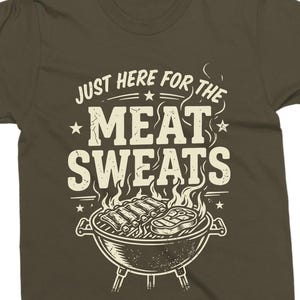 May include: Olive green t-shirt with the text "JUST HERE FOR THE MEAT SWEATS" in a vintage style. The design includes a grill with ribs and a steak, with flames rising above.