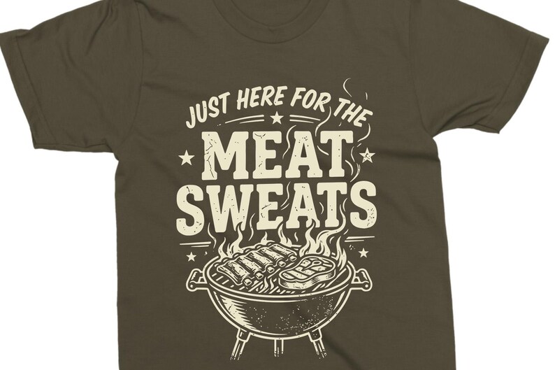 May include: Olive green t-shirt with the text "JUST HERE FOR THE MEAT SWEATS" in a vintage style. The design includes a grill with ribs and a steak, with flames rising above.