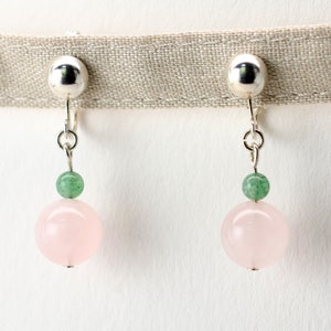 May include: A pair of silver clip-on earrings with a pink and green stone design. The earrings feature a large pink round stone with a smaller green round stone above it.