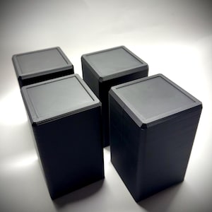 以下が含まれることがあります： 3Dプリンターで印刷された黒い正方形の箱が4つあります。箱は積み重ねられています。