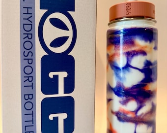 Peut inclure: Une bouteille HOGG HydroSport de 32oz avec une finition marbrée blanche, bleue et orange, dotée d'un couvercle couleur pêche avec le mot HYDRO imprimé dessus et une paille blanche, à côté de sa boîte d'emballage en carton blanc d'origine.