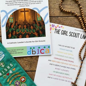 Może przedstawiać: Zestaw materiałów harcerskich, w tym przewodnik zatytułowany "My Promise, My Faith" i strona z "The Girl Scout Law". Zielona chusta z odznakami i drewniany różaniec są również obecne. Przedmioty są na drewnianej powierzchni.