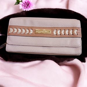 May include: A light beige leather wallet with a brown and gold braided design and the text "Signature" in gold lettering.