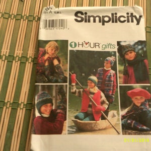 May include: A Simplicity sewing pattern booklet with a cover featuring a colorful illustration of children wearing various knitted hats and winter clothing. The pattern is titled "1 Hour Gifts" and includes sizes S, M, and L.