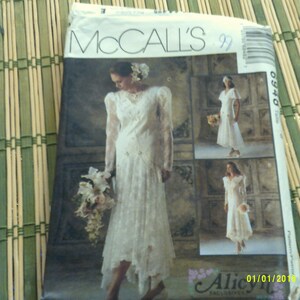 May include: A McCall's sewing pattern for a wedding dress. The pattern is for a white dress with a lace overlay and a long skirt. The pattern number is 0340.