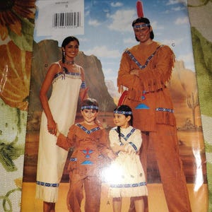 May include: A Butterick sewing pattern envelope featuring four individuals wearing tan and cream-colored fringe costumes with blue, red, and white geometric trim. The costumes include dresses, tunics, and pants, with some headbands and feathers.