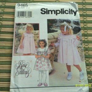 Puede incluir: Patrón de costura Simplicity para vestidos de niña. El patrón presenta ilustraciones de niños con varios diseños de vestidos. El paquete incluye el texto "Rare Editions" y el logotipo de Simplicity. El fondo es verde claro.