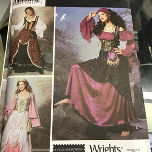 Puede incluir: Un patrón de costura Simplicity Costumes para un disfraz de pirata. El patrón incluye tres opciones de disfraces diferentes: una falda de cuadros rojos y negros con una blusa blanca, un vestido rosa y blanco con una blusa blanca y una falda morada con una parte superior negra. El patrón es para las tallas 6, 8, 10 y 12.