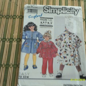 Peut inclure: Patron de couture Simplicity pour vêtements d'enfants. Le patron comprend trois modèles : une robe en jean bleu, une robe rouge à manches longues et une robe blanche à imprimé coloré. Le patron est intitulé "Crayola Kids Favorite Colors" et comprend des instructions de couture faciles.