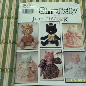 May include: Simplicity sewing pattern 0685, Jiffy Six Pack, featuring six different stuffed animal patterns: a cat, a cat wearing a bow tie, a cat wearing a dress, a cat wearing a dress with flowers, a cat wearing a dress with polka dots, and a cat wearing a dress with a bow.