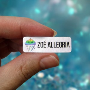 May include: White iron-on label with a rainbow cloud with a smiling face and raindrops. The label says "ZOÉ ALLEGRIA".