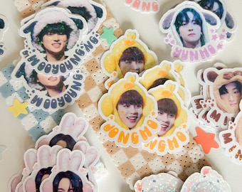 Puede incluir: Una colección de pegatinas brillantes y coloridas con ídolos del K-pop. Cada pegatina tiene el nombre y la imagen de un ídolo diferente, incluyendo 'San', 'Yeosang', 'Wooyoung', 'Yunho', 'Jongho', 'Seonghwa' y 'Hongjoong'.