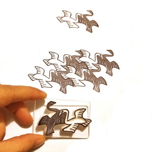 May include: A set of black and white rubber stamps featuring a design of birds in flight. The stamps are arranged in a pattern of overlapping birds, creating an optical illusion. The stamps are on a white surface.