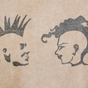 Puede incluir: Dos ilustraciones en tinta negra de perfiles humanos estilizados sobre un fondo beige. Un perfil presenta una cresta puntiaguda, el otro tiene el pelo rizado. La obra de arte evoca una estética punk rock.