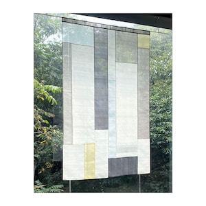 May include: A white wall hanging with a geometric pattern of squares and rectangles in shades of gray, blue, and yellow.