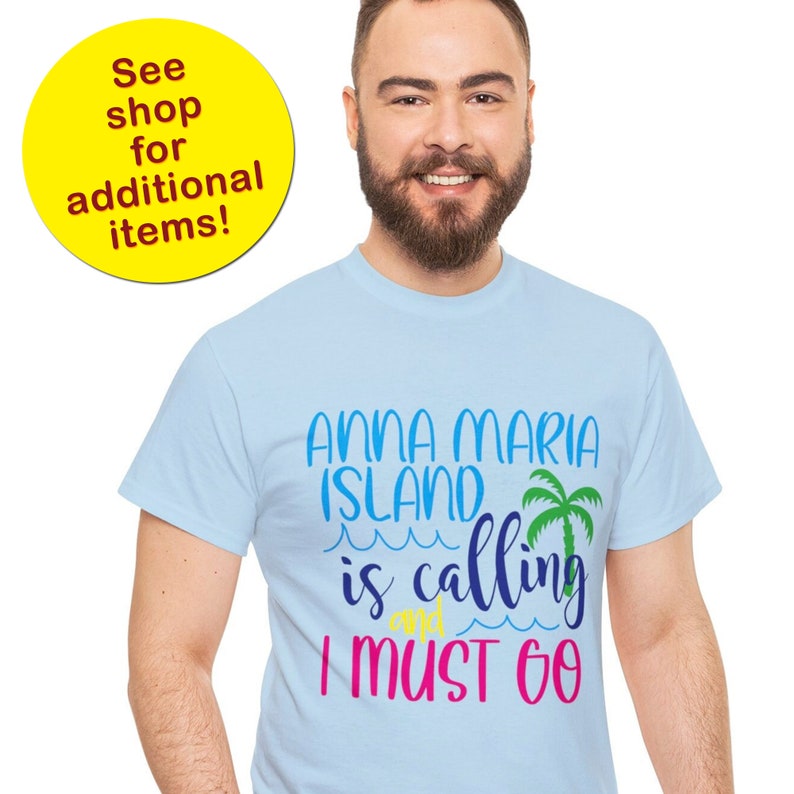 K&ouml;nnte beinhalten: Hellblaues T-Shirt mit dem Text "Anna Maria Island is calling and I must go" in bunten Buchstaben. Neben dem Text befindet sich eine Palmengrafik.