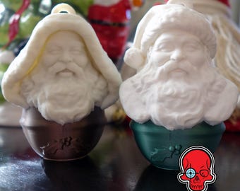 Può includere: Due addobbi natalizi in ceramica bianca a forma di testa di Babbo Natale. Gli addobbi sono decorati con una barba e un cappello bianchi. L'addobbo a sinistra ha una base marrone e l'addobbo a destra ha una base verde.