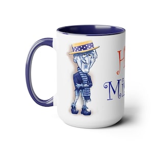 May include: White ceramic coffee mug with a blue rim and handle. The mug features a cartoon illustration of a man wearing a blue and white striped scarf and a straw hat with white polka dots. The text "Happy" in orange and "Mister" in blue is printed on the mug.