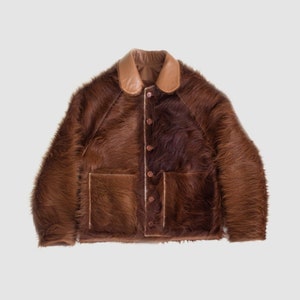 May include: A brown leather jacket with a brown fur lining and a brown leather collar. The jacket has a button closure and two pockets.