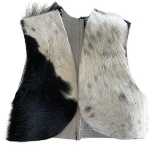 May include: A black and white cowhide vest with a gray suede lining. The vest is unfinished and has raw edges.