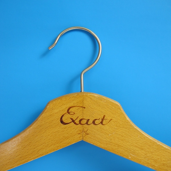 Vintage houten kleerhanger. Ongebruikelijke vorm, met lusgroeven en 'Exact' reclamemerk. Vintage reclamehanger