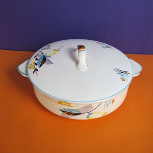 Könnte beinhalten: Weiße Keramik-Servierplatte mit Deckel und Griff. Die Platte hat ein florales Design mit blauen, orangefarbenen und gelben Akzenten.