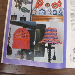 May include: A crochet pattern for a floral mobile with pink, red, and blue flowers. The pattern includes instructions for making a lampshade with pink and blue crochet.