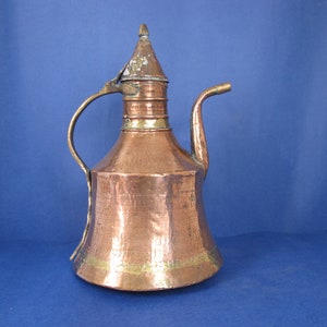 May include: A copper teapot with a hammered finish and a brass spout and handle. The teapot has a domed lid with a finial.