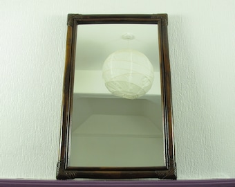 May include: A brown wooden framed mirror with a white paper lampshade hanging from the ceiling reflected in the mirror.