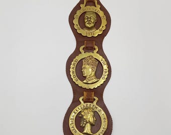 Vintage Royal horse brasses on a brown leather strap. George V, Edward VII and Elizabeth II